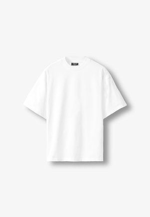 Bela kratka majica z razširjenimi rokavi in okroglim izrezom, z črno etiketo na notranji zadnji strani ovratnika, prikazana na svetlem ozadju.