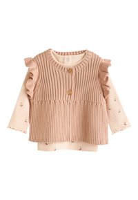 Pink ribbed knit sleeveless top with wooden buttons layered over a long-sleeve cream shirt with small floral prints and ruffled sleeves.