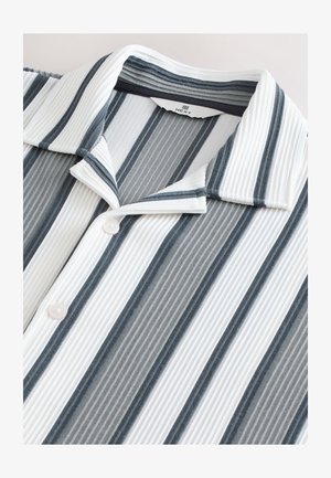Camicia con bottoni in morbido tessuto a coste con sottili strisce grigie e bianche. Presenta un colletto a punta e bottoni perlacei.
