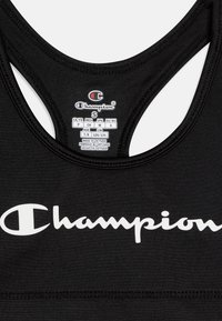 Melnā sporta krūšturis ar racerback dizainu, mīkstu audumu un balto "Champion" logo, kas apdrukāts priekšpusē. Iekļauta kopšanas etiķete.