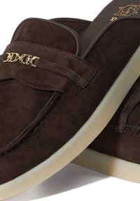 Bruine suède instappers met een gouden kettingaccent, voorzien van een rubberen zool en gestikte details, die een soepele textuur en klassiek ontwerp tonen.