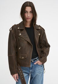 Braune Leder-Bikerjacke mit silbernen Beschlägen, asymmetrischem Reißverschluss und Schulterklappen. Verfügt über Seiten- und Brusttaschen, lockere Passform.