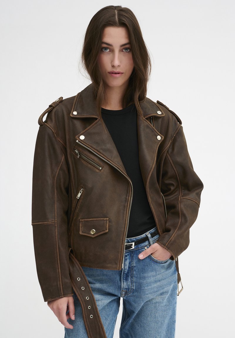 Braune Leder-Bikerjacke mit silbernen Beschlägen, asymmetrischem Reißverschluss und Schulterklappen. Verfügt über Seiten- und Brusttaschen, lockere Passform.