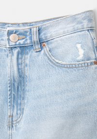 Svijetloplave traperice s visokim strukom, metalnim zatvaranjem na dugme i istrošenim detaljima na prednjoj džepu.