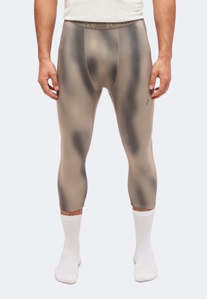 Homme portant un legging moulant trois-quarts avec un motif dégradé gris et noir et des chaussettes blanches.
