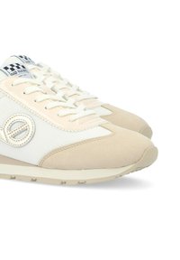 Sneaker beige con una combinazione di materiali in suede e mesh, dettaglio del logo rotondo, lacci bianchi e suola in gomma testurizzata.