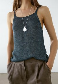 Débardeur bleu foncé en maille avec fines bretelles, doté d'une coupe décontractée et d'un tissu texturé, associé à un pantalon plissé marron clair.