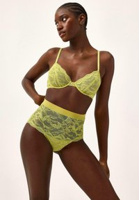 Limegrøn blonde lingeri sæt bestående af en ikke-pudret bralette med justerbare stropper og højtaljede trusser med blomstermønstre og elastisk talje.