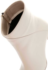 Crème leren enkellaars met een gladde textuur, spitse neus, ritssluiting en minimale stikdetails.
