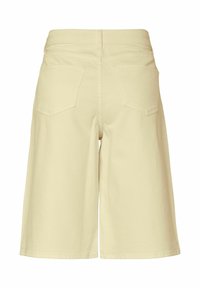 Béžové denimové šortky po kolená s dvoma zadnými vreckami, pútkami na opasok a rovnostrihým strihom, zobrazené zozadu na bielom pozadí.