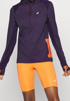 Atletisk outfit med en mørkelilla langærmet lynlåstrøje og lyse orange tætsiddende shorts, begge med hvide Asics-logoer.
