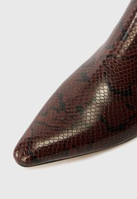 Shoe de bico fino em falso couro de serpente bordeaux escuro, apresentando uma superfície texturizada com um acabamento brilhante e detalhes discretos em preto.