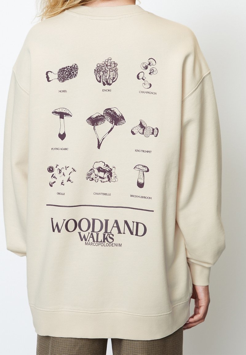 béžová mikina s potiskem vzadu z různých houb v hnědém inkoustu, označené názvy, a textem "WOODLAND WALKS" ve spodní části.