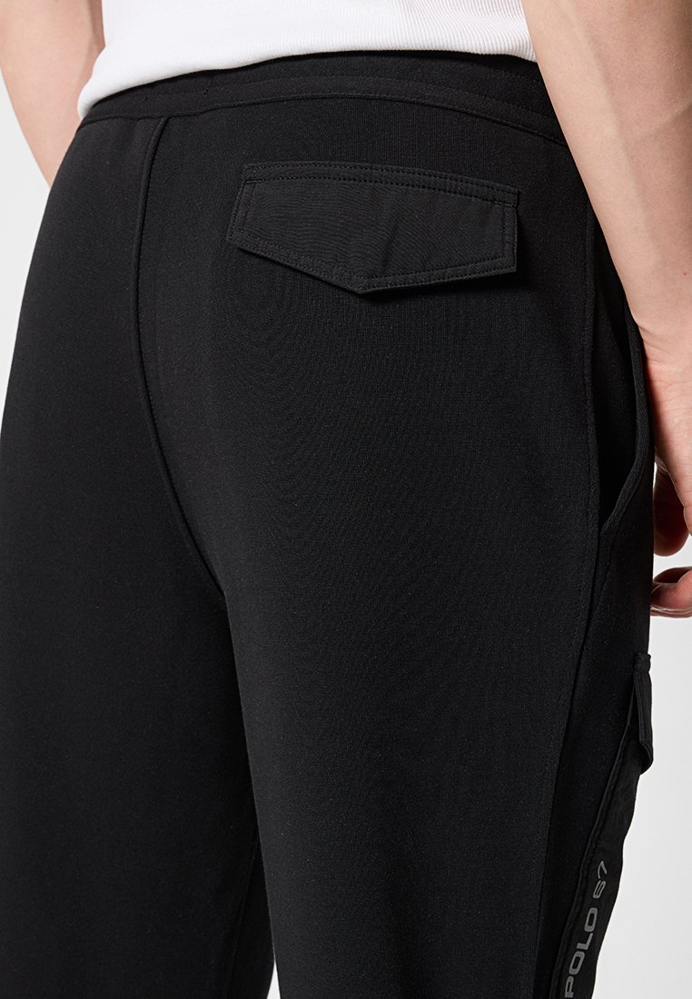 Czarne spodnie dresowe o dopasowanym kroju, z tylną kieszenią, szwem bocznym oraz detalem z logo na dolnej lewej nodze.