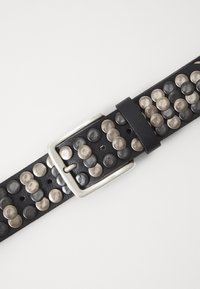 Ceinture en cuir noir avec des clous métalliques en argent et gris foncé, dotée d'une boucle rectangulaire argentée et de plusieurs trous pour l'ajustement.
