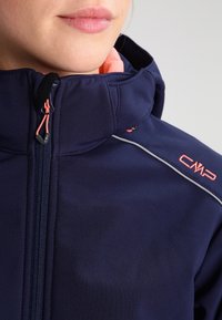 Marineblaue Softshelljacke mit hohem Kragen, pinken Akzenten, einem Frontreißverschluss und CMP-Logo auf der Schulter. Mit glatter Textur und tailliertem Design.