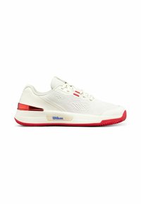 Zapatilla deportiva blanca con parte superior de malla, acentos rojos en la suela y el lateral, y un logo azul de "Wilson" en la entresuela. Diseño ligero.