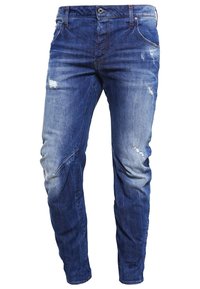 Jean en denim bleu avec une coupe slim, légère décoloration et petites zones usées sur les cuisses et les genoux.