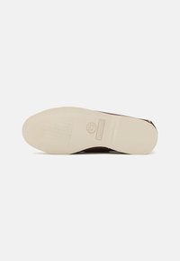 Braunes Schuhwerk mit einer nicht markierenden weißen Gummisohle. Die Sohle hat ein strukturiertes Muster und zeigt ein Timberland-Logo.