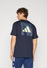 Camiseta de manga corta azul marino con un gran gráfico a rayas en verde claro en la parte posterior. Tejido suave con un corte regular.