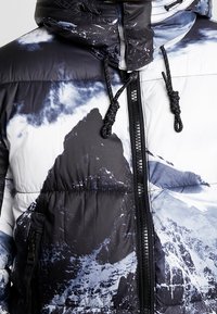 Černobílá prošívaná bunda s potiskem hor, zipem, nastavitelnou kapucí a texturovanou látkou s elastickými stahovacími šňůrkami.