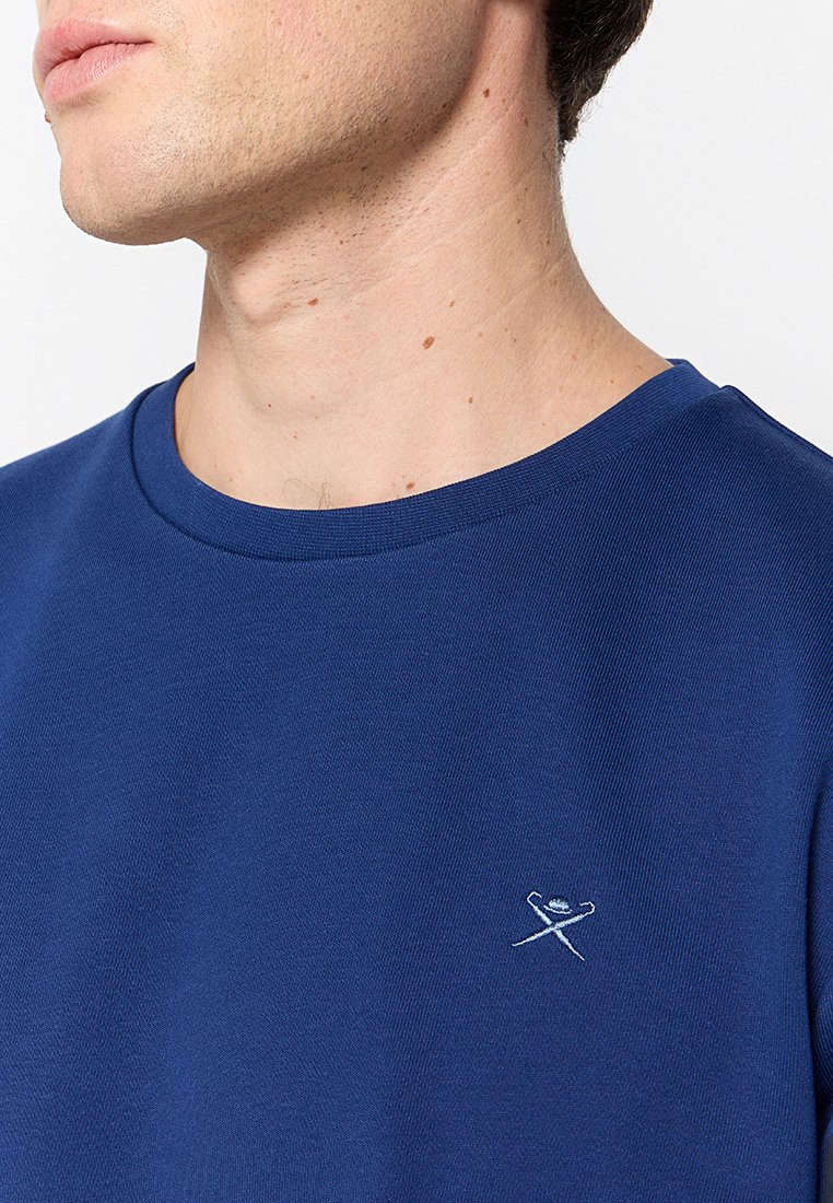 Camiseta de manga corta en azul marino, hecha de tela texturizada, con un cuello redondo y un pequeño logo bordado en el pecho.