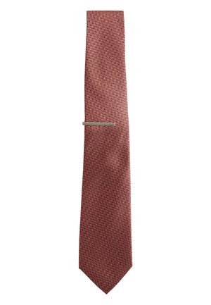 Rote strukturierte Krawatte mit einem kleinen silbernen Krawattenclip, der horizontal nahe der Mitte auf weißem Hintergrund positioniert ist.