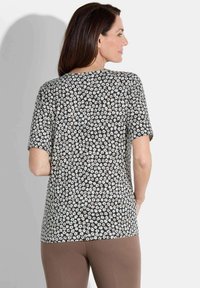 Schwarzes Kurzarm-Top mit floralem Muster und kleinen weißen und rosa Blumen. Weicher Stoff, lockere Passform, runder Ausschnitt und nahtloser Rücken.