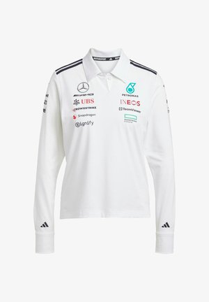 Bijela dugih rukava polo majica s ovratnikom, koja ima crne pruge i više logotipa sponzora različitih boja sprijeda i na rukavima.