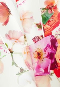 Blumenmusterstoff mit weißem Hintergrund. Enthält rosa, orange und lila Blumen. Goldener Reißverschlussdetails in der Mitte. Glatte Textur.