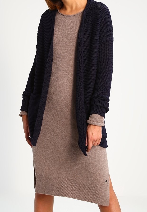 Námořnický pletený cardigan s otevřeným předním dílem, texturovanou tkaninou a žebrovanými rukávy spárovaný s přiléhavým béžovým šaty s bočními rozparky.