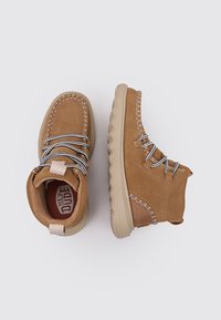 Stivali alla caviglia in suede beige con finitura testurizzata, caratterizzati da lacci grigi, cuciture a contrasto e una robusta suola beige.
