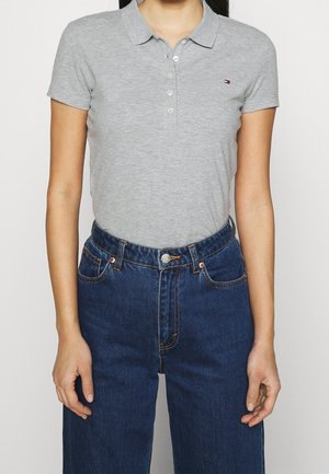 Grijze polo met een vlakke kraag, korte mouwen en knoopsluiting. Gecombineerd met hoog-uitsneden, donkerblauwe denim jeans met voorzakken.