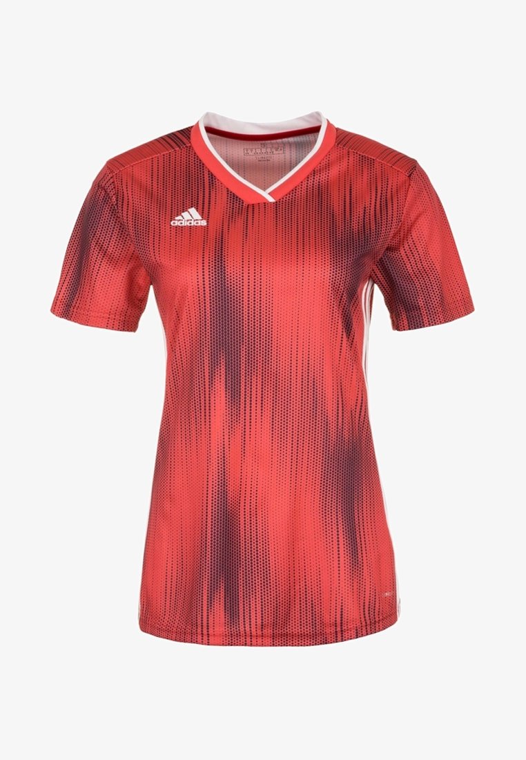 Punainen lyhythihainen jalkapallopaita V-kauluksella, jossa on tummemmanpunaisista pisteistä koostuva liukuvärjätty kuvio. Valkoiset yksityiskohdat kauluksessa ja sivuilla.