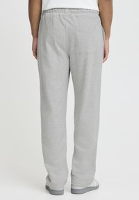 Pantalon de survêtement gris en tissu doux, doté d'une taille élastique, d'une poche arrière et d'une coupe décontractée avec jambes fuselées.