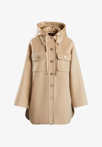 Bežs flīsa mētelis ar izšūtu kapturi, pogu aizdari, divām krūšu kabatām un vaļīgu piegriezumu ar noapaļotu apakšmalu.