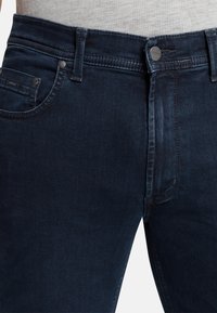 Dunkelblaue Denim-Jeans mit Slim Fit, ausgestattet mit einem Reißverschluss, fünf Taschen und dezenten Nähdetails. Glatte Textur.