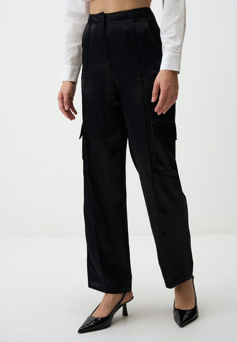 Zwarte satijnen cargobroek met een losse pasvorm, voorzien van zijzakken en een gladde textuur. Gecombineerd met zwarte puntige slingback hakken.