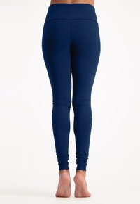 Marineblaue Leggings aus dehnbarem Material, mit einem breiten Bund und knöchellangem Design. Glatte Textur ohne sichtbare Muster.