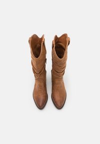 Botas de vaquero de cuero marrón con un diseño caído, punteras afiladas y cremalleras laterales. Textura suave sin patrones ni acentos visibles.