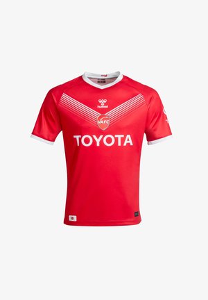Camiseta de fútbol roja con detalles blancos, con rayas horizontales y los logotipos de "Hummel", "VAFC" y "Toyota". Mangas cortas, cuello redondo.
