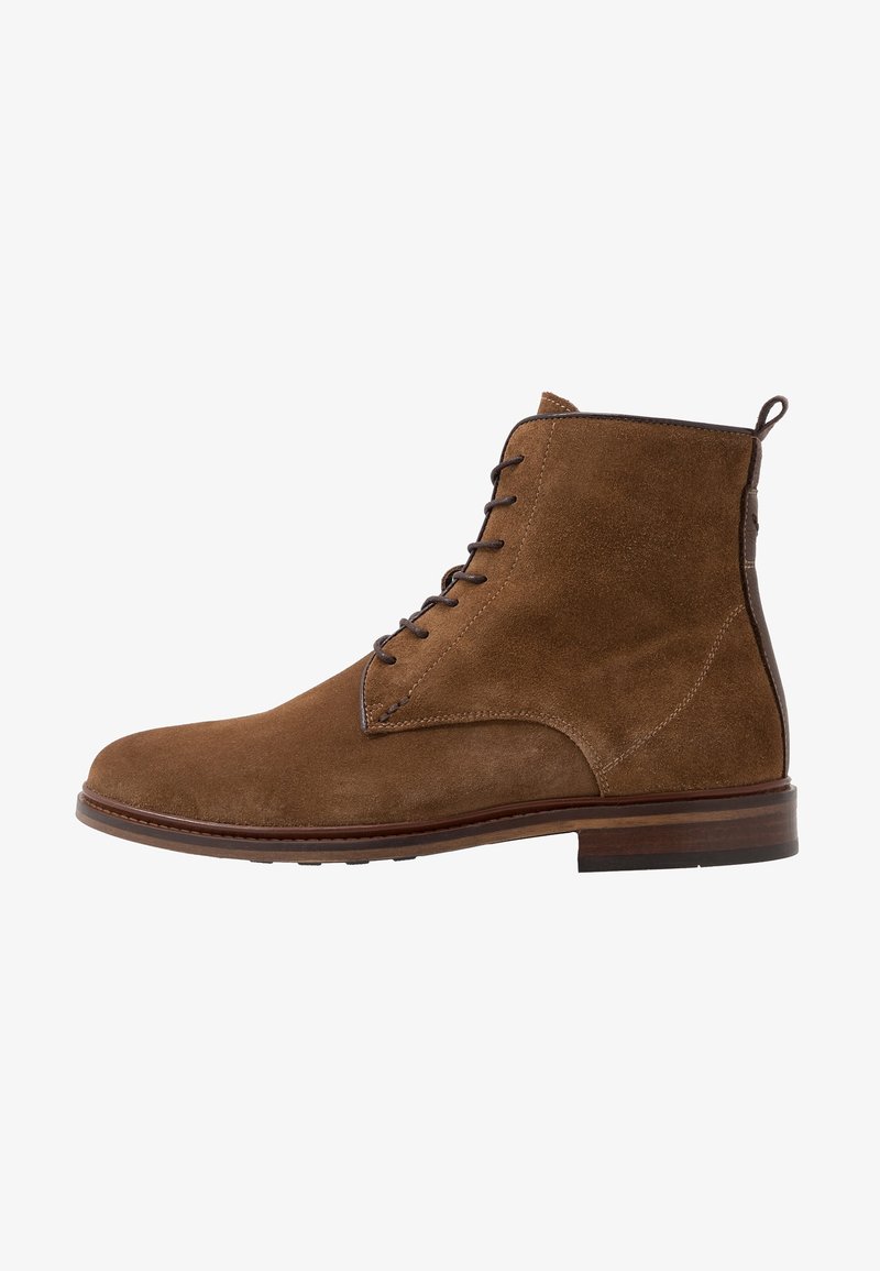 Bottine en cuir suédé marron avec des lacets marron foncé, languette à l’arrière et semelle en bois superposée, vue de l'extérieur.
