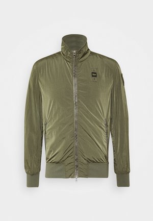 Lightweight olive green zip-up jacket with high collar, ribbed cuffs and hem, and a small black logo patch on the chest.