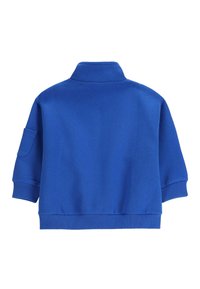 Niebieska bluza z wysokim kołnierzem, krótkimi rękawami i prążkowanymi mankietami. Przód ozdobiony naszywką na lewym rękawie. Wykonana z miękkiego materiału bawełnianego.