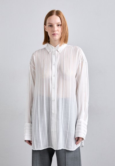 Chemise blanche rayée à boutons avec une coupe décontractée, dotée d'un col, de manches longues et d'une texture transparente. Associée à un pantalon gris.