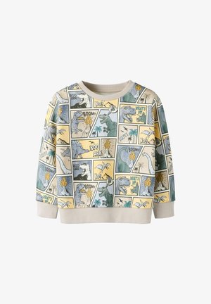 Pull avec un imprimé dinosaure de style bande dessinée aux couleurs pastel. Le matériau est doux avec un col côtelé. Le design comprend des bulles de dialogue ludiques.