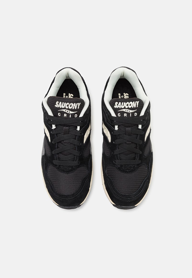 Le sneaker nere presentano una tomaia in rete e suede, lacci rotondi, colletto imbottito e un logo bianco sulla linguetta. Suola in gomma texturizzata.