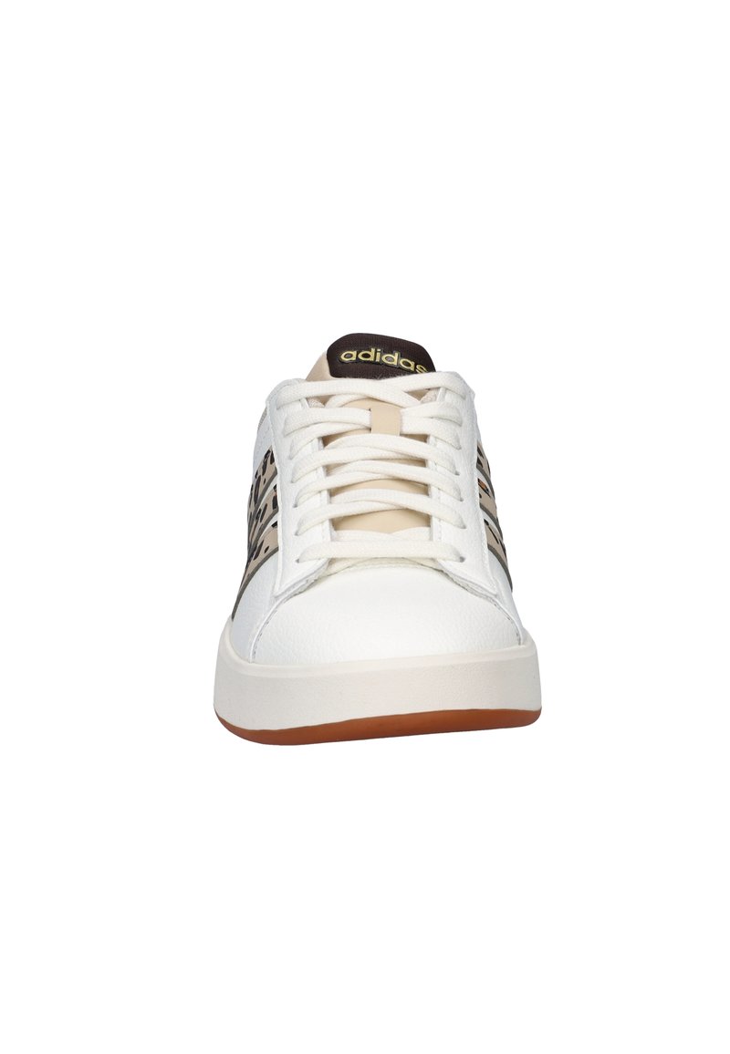White athletic shoe with textured leather upper, brown accents, and tan rubber sole. Features beige laces and branded tongue.