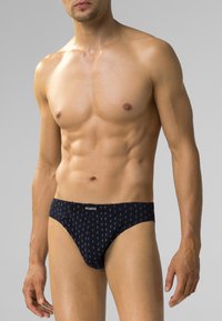 Czarne majtki męskie wykonane z gładkiego materiału, z małym, powtarzającym się wzorem diamentów. Elastyczny pas z widocznym logo "ATLANTIC".
