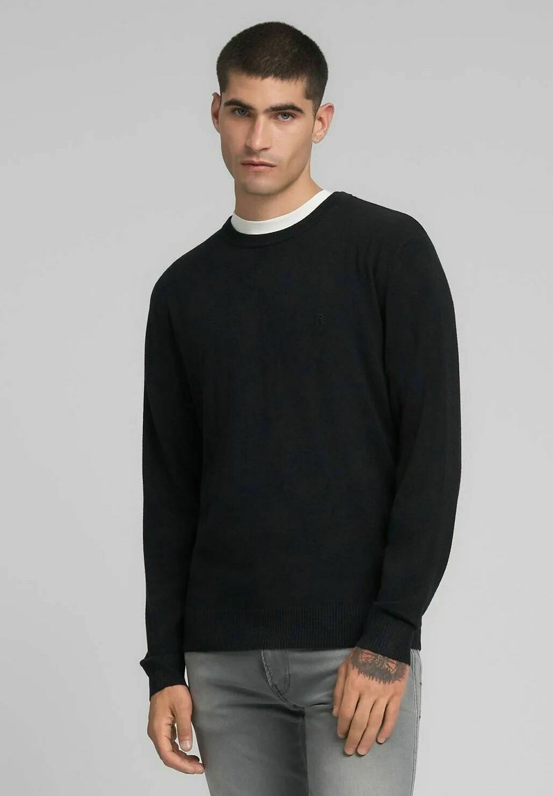 Zwarte trui met lange mouwen, geribbelde manchetten en zoom, ronde hals met een witte accent, gemaakt van zachte stof, met een klein logo op de borst.